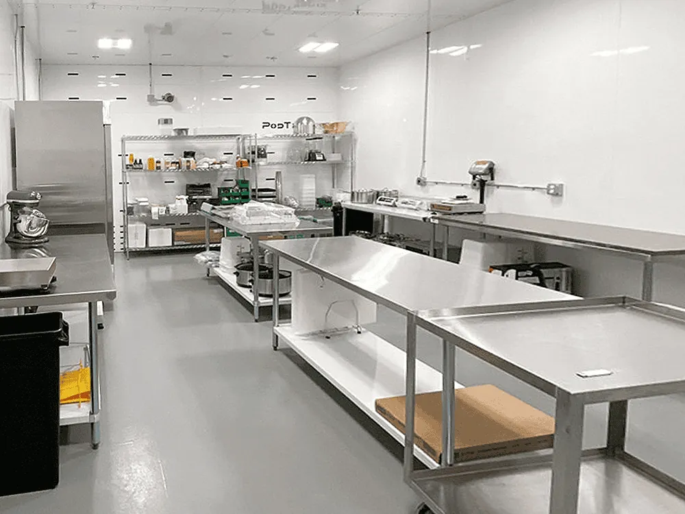 Adjacent post-processing room outfitted with stainless steel work tables, mixers, and modular shelving for downstream operations.